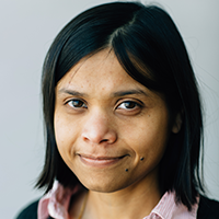 Woman smiling with dark hair, portrait of Sushmita Roy.