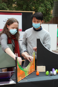 A man and a woman demonstrating an inertia machine at a black table.