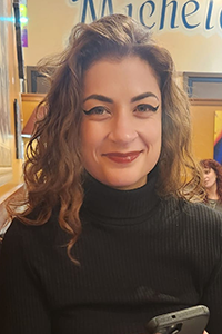 Julia Nakhleh Julia Nakhleh portrait. Woman with long wavy hair in a black turtleneck.