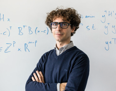 Alberto Del Pia in front of a white board with mathematical notation.Photo by Joel Hallberg