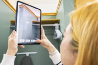 PhD student Lee holds up a device with the ARHART app to measure living spaces.