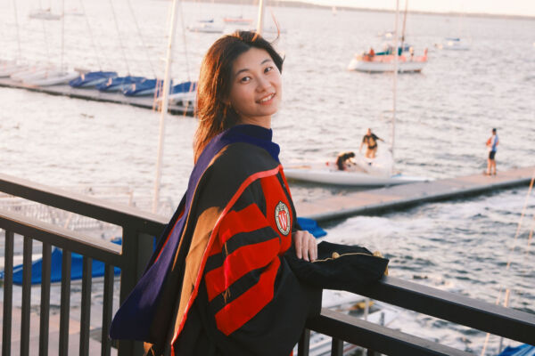Nan Jiang in full PhD regalia overlooking Lake Mendota on the University of Wisconsin campus