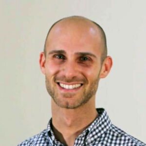 Photo of a man smiling wearing a blue checkered shirt