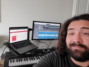 Collin Hemme in front of computer screens with wavelengths and also a piano.