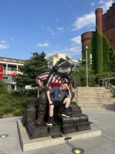 Dekun Zhou sitting on a rendering of Bucky Badger at the Memorial Terrace