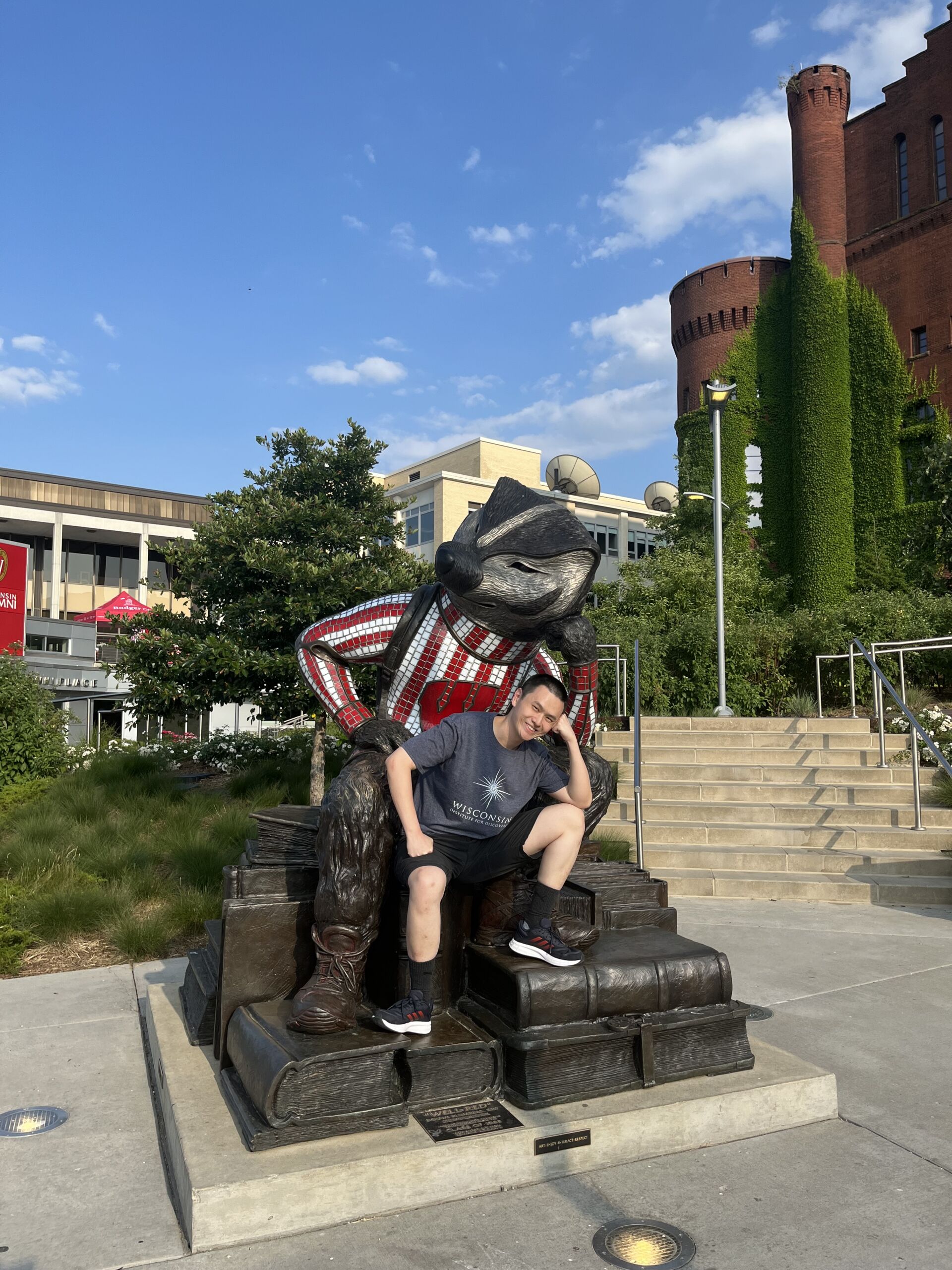 Dekun Zhou sitting on a rendering of Bucky Badger at the Memorial Terrace