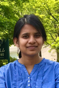 RubayaRashid Rubaya Rashid portrait. Dark haired woman in a blue shirt
