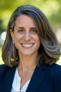 medium-Michal Engelman Headshot 2026 Michal Engelman portrait woman with side-swept hair in a blue blazer