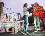 Scientists stand on a podium outside wearing casual clothes at dusk